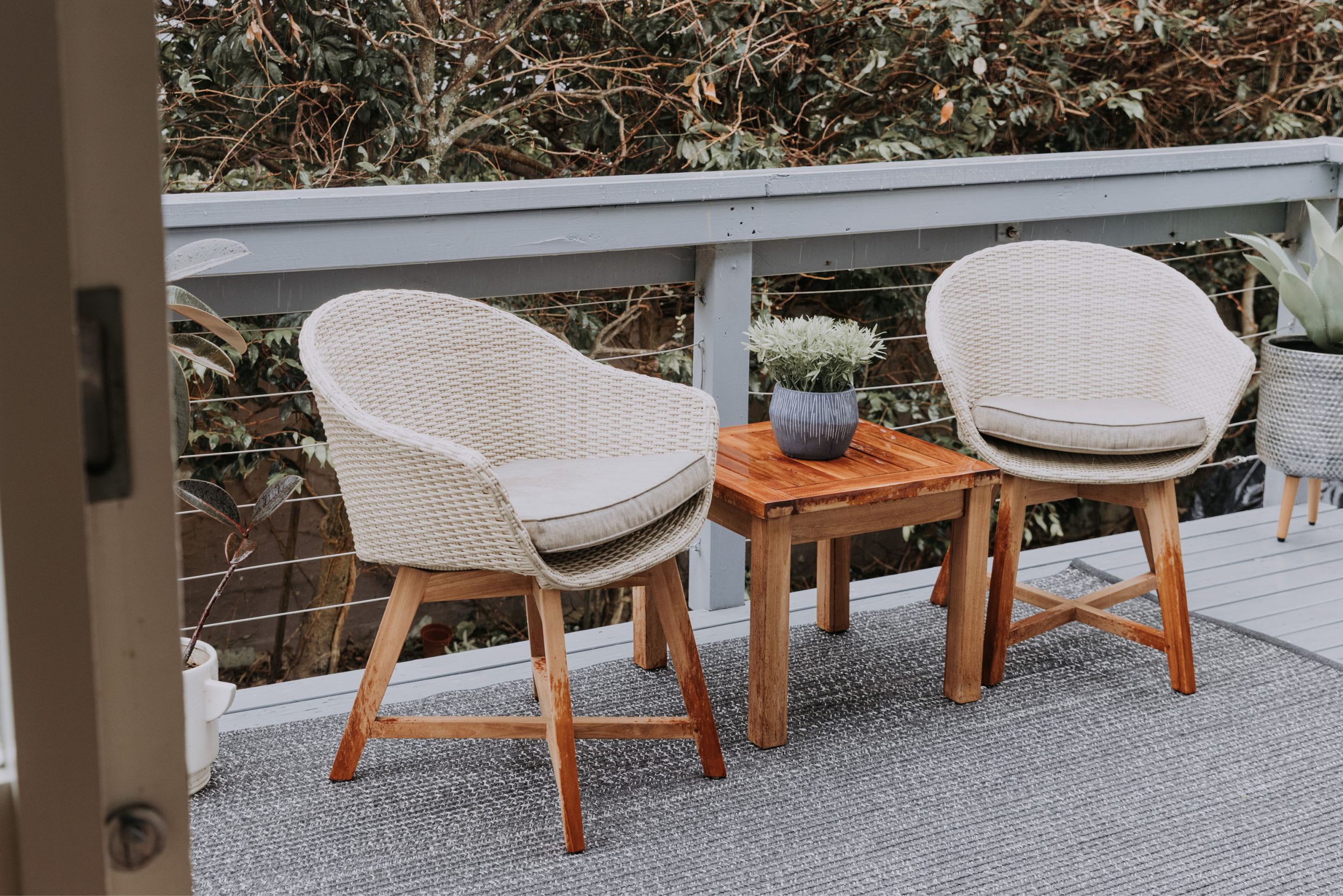 户外柚木和全天候的柳条椅子和小咖啡桌与植物在阳台上